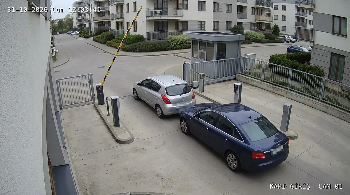 Example camera image: a dark blue car follows a silver car through the raised barrier